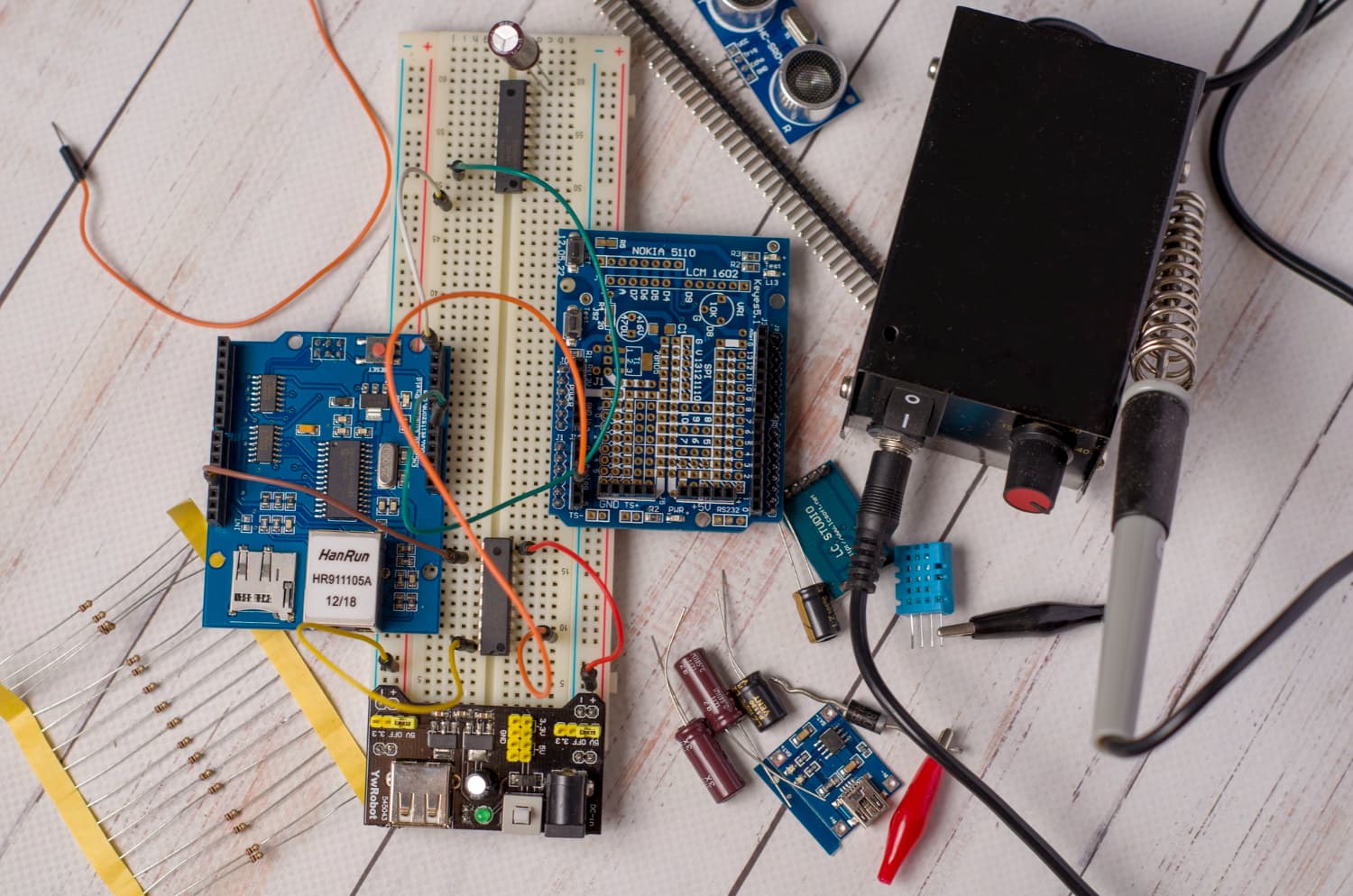 Electronic component workbench — microcontrollers, sensors, breadboard prototyping, and soldering station.